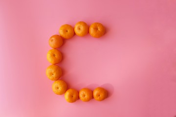 Small Chinese Mandarin Oranges arranged in heart shape isolated on pink background with copy space. Shatang Mandarin (Orange Red)