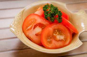 sliced tomato with parsley on brown bowl