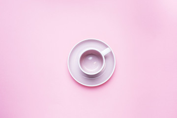 An empty coffee Cup with a saucer in the center of the table on a pink background with copy space. Top view. minimalism.