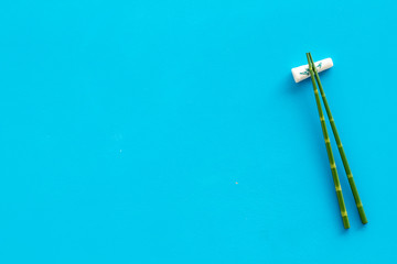 Chopsticks - green wooden utensil for sushi and rolls - on blue background top-down copy space