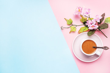Obraz na płótnie Canvas A Cup of coffee with milk and branch with flowers and leaves.on a pink pastel background with copy space. Flat lay.
