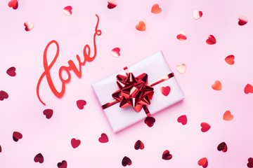 Concept Valentine's Day. Pink background with red hearts and gift. Flat lay copy space. Greeting card and gift.