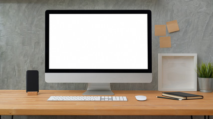 Close up view of blank screen desktop computer with sticky note, frame and office supplies with loft grey wall