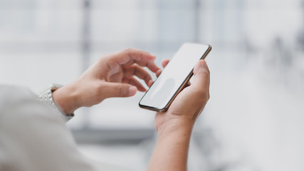 Close up view of  businessman touching  blank screen smartphone with blurred office room
