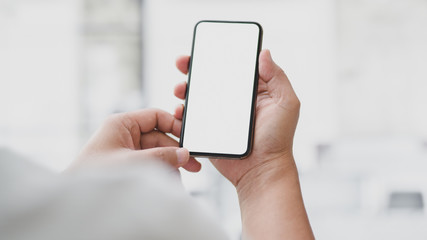 Cropped shot of businessman touching  blank screen smartphone with blurred office room