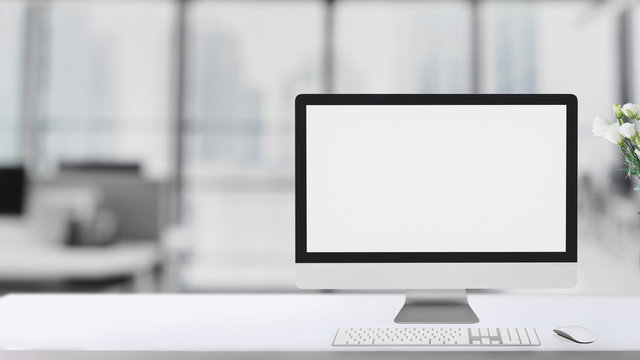 Cropped shot of simple workspace  with blank screen computer on white table with blurred office room