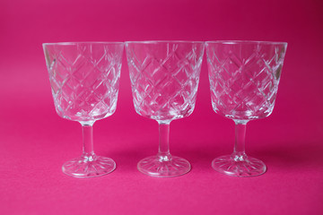 Three macro wine glasses on pink background with copy space.