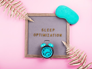 Sleep optimization text composed on wooden letter board with green sleeping mask, alarm clock,...
