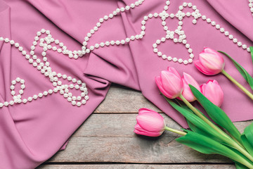Beautiful tulip flowers with beads and fabric on wooden background