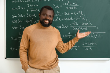 African-American math teacher near blackboard in classroom