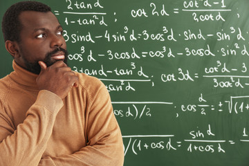 Thoughtful African-American math teacher near blackboard in classroom © Pixel-Shot