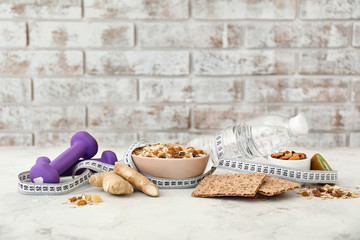 Different healthy food with measuring tape and dumbbells on table. Diet concept