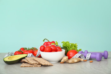 Different healthy food with measuring tape and dumbbells on table. Diet concept