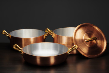Shiny vintage copper cookware over dark background
