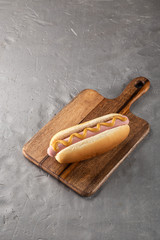 Hot dogs with mustard on a wooden board. Hot dogs served on a stone table. Free space for text