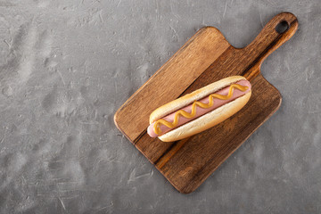 Hot dogs with mustard on a wooden board. Hot dogs served on a stone table. Free space for text