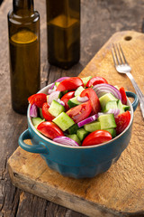 Salad of tomatoes and cucumbers in a plate on a wooden table