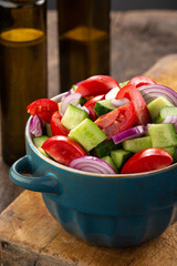Salad of tomatoes and cucumbers in a plate on a wooden table