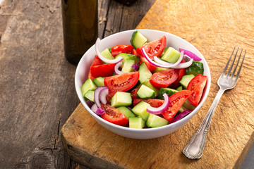 Salad of tomatoes and cucumbers in a plate on a wooden table