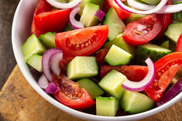 Salad of tomatoes and cucumbers in a plate on a wooden table