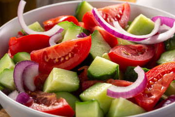 Salad of tomatoes and cucumbers in a plate on a wooden table