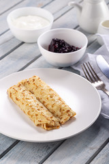 Homemade pancakes with cream cheese and berry jam on a plate, selective focus. Wooden table