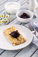Homemade pancakes with cream cheese and berry jam on a plate, selective focus. Wooden table