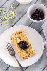 Homemade pancakes with cream cheese and berry jam on a plate, selective focus. Wooden table