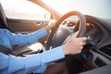 Woman driving her car, hands holding steering wheel.