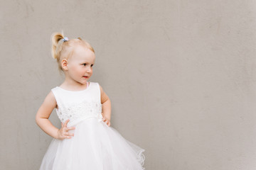 Fototapeta na wymiar Happy baby girl in white dress on grey background