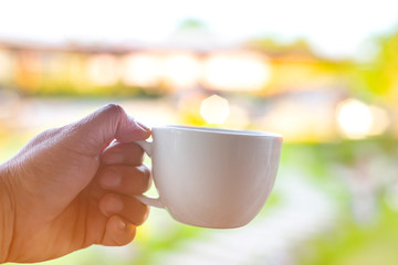 Fototapeta na wymiar A white coffee cup in hand on blur background