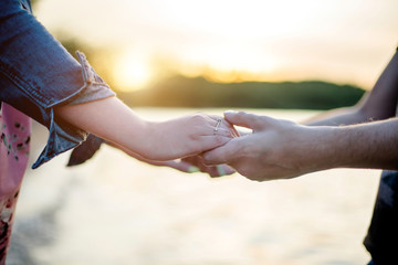 Guy and girl holding hands on the background of sea water
