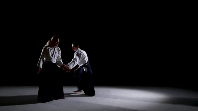 Two Aikido Masters participants of the training in special clothes of aikido hakama work out the methods of single combat. Slow motion.