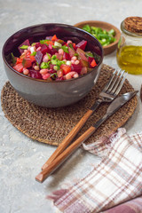Close-up of vinaigrette salad on a wicker stand with traditional style cutlery