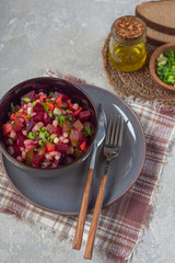 Close-up of vinaigrette salad in a dark plate with traditional cutlery