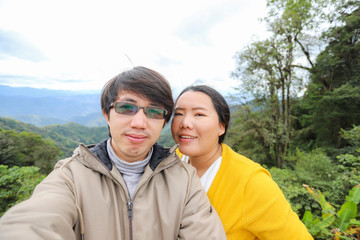 Asian couple taking selfie on view point with beautiful nature background