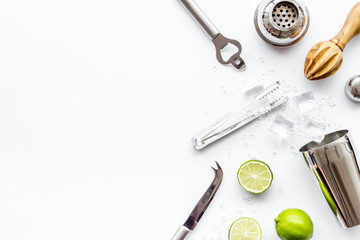 Bar background. Tools and ingredients for cocktails. Shaker, lime, ice on white background top-down frame copy space