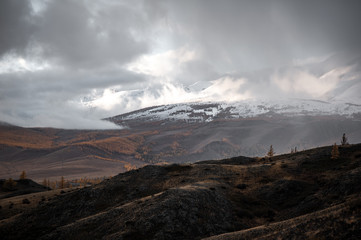 gloomy landscape at sunset day of a giant snowy mountain range with glaciers towering over the autumn valley
