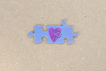 Blue puzzle with a red heart on the cardboard, craft paper background. Valentine's day stock photo...