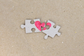Puzzle with a red heart on the cardboard, craft paper background. Two disconnected halves....