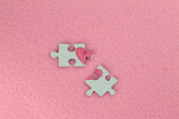 Puzzle with a red heart on the pink felt background. Two disconnected halves. Valentine's day stock photo with empty space for your text. For web, print, postcard, background and wallpaper 