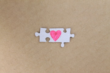 Puzzle with a red heart on the cardboard, craft paper background. Valentine's day stock photo with...