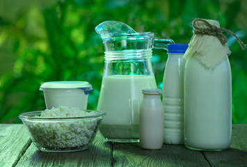 dairy products stand on a wooden table against the background of nature