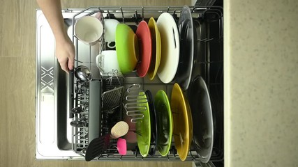 girl puts dishes in the dishwasher and closes it