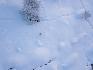 Aerial view of backcountry freeride skier leaving traces in powder snow. Concept of backcountry mountaineering.