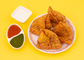 Indian Street Food Samosa or Samosas is a Crispy And Spicy Triangle Shape Snack Which Has Crisp Outer Layer of Maida & Filling of Mashed Potato, Peas And Spices. Served With Chutney, Ketchup or Curd