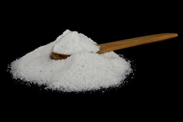Fototapeta na wymiar A pile of salt in a wooden spoon isolated on a black background close-up.