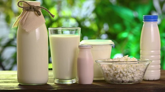 dairy products stand on a wooden table against background of nature