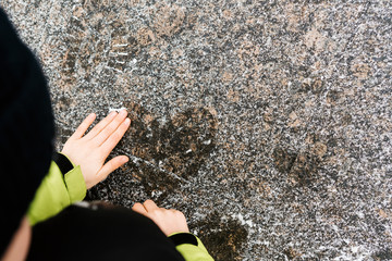 Hand of a boy drawing a heart on snowy asphalt. Valentine's day concept.
