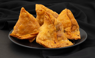 Indian Street Food Samosa or Samosas is a Crispy And Spicy Triangle Shape Snack Which Has Crisp Outer Layer of Maida & Filling of Mashed Potato, Peas And Spices. Served With Chutney, Ketchup or Curd